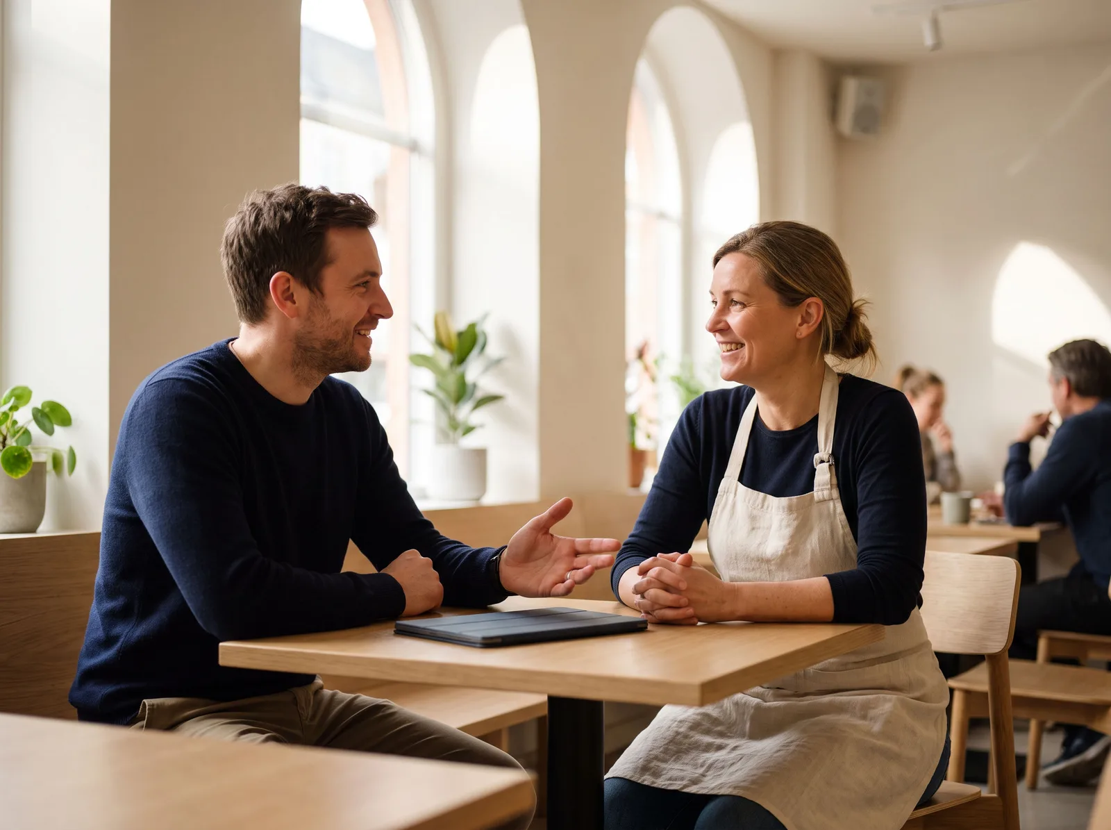 A bookkeeper explaining numbers to a café owner across a table